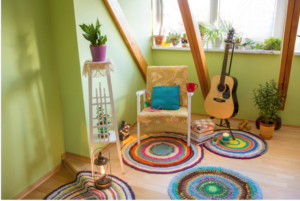 A green room with a chair, plant and an acoustic guitar. A place to practice guitar.