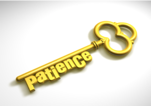 A gold key with the word patience on it.