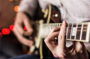 A man sitting down playing a Gibson Guitar.