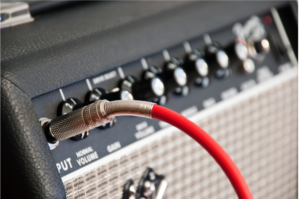 Fender amplifier with a red guitar cable plugged into it.