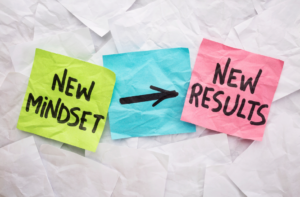 Three post it notes. One green, blue and red. With the words New Mindset, and arrow pointing to the word New Results.