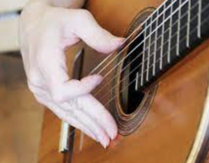 Fingers anchored to the guitar body of a classical guitar.